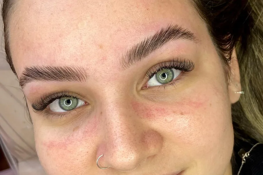 Cliente de olhos verdes com sobrancelhas alinhadas e extensão de cílios